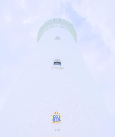 Ein weißer Leuchtturm vor einem weitgehend weißen, wolkigen Himmel, fotografiert aus der Froschperspektive