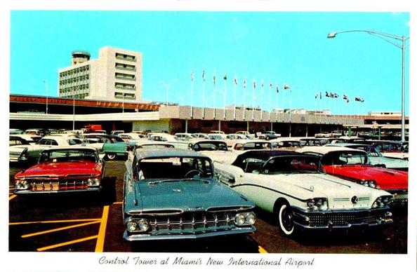 Outside the terminal and there are many late 1950's cars. I see to 1959 Impalas and a 1958 Buick. In the background is the terminal and hotel.