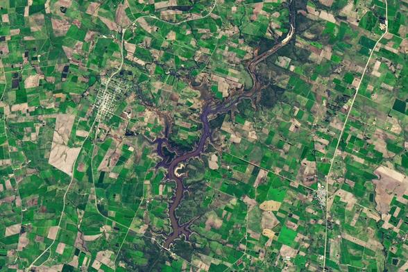 image of landscape with farmed fields surrounding a dammed river filled with water.