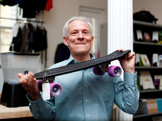 Vincent Stanley hoists a black Bureo® skateboard made from NetPlus recycled nylon. 
