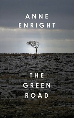 The cover of "The Green Road" by Anne Enright. It shows a rocky landscape in the front, with a cloudy sky above it. Rusing out of the line between land and sky is a single solitary tree, completely bare of leaves.