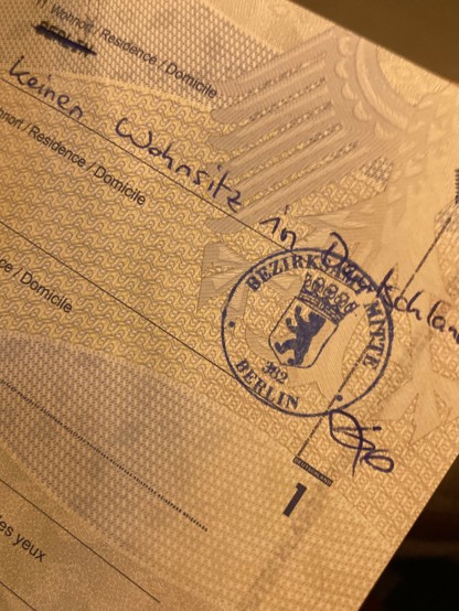 Section of my passport page defining the residence, which was Berlin but now needs to reflect „no residence in Germany“. The civil servant took a ruler to strike Berlin out and wrote it by hand with a „fancy“ stamp.