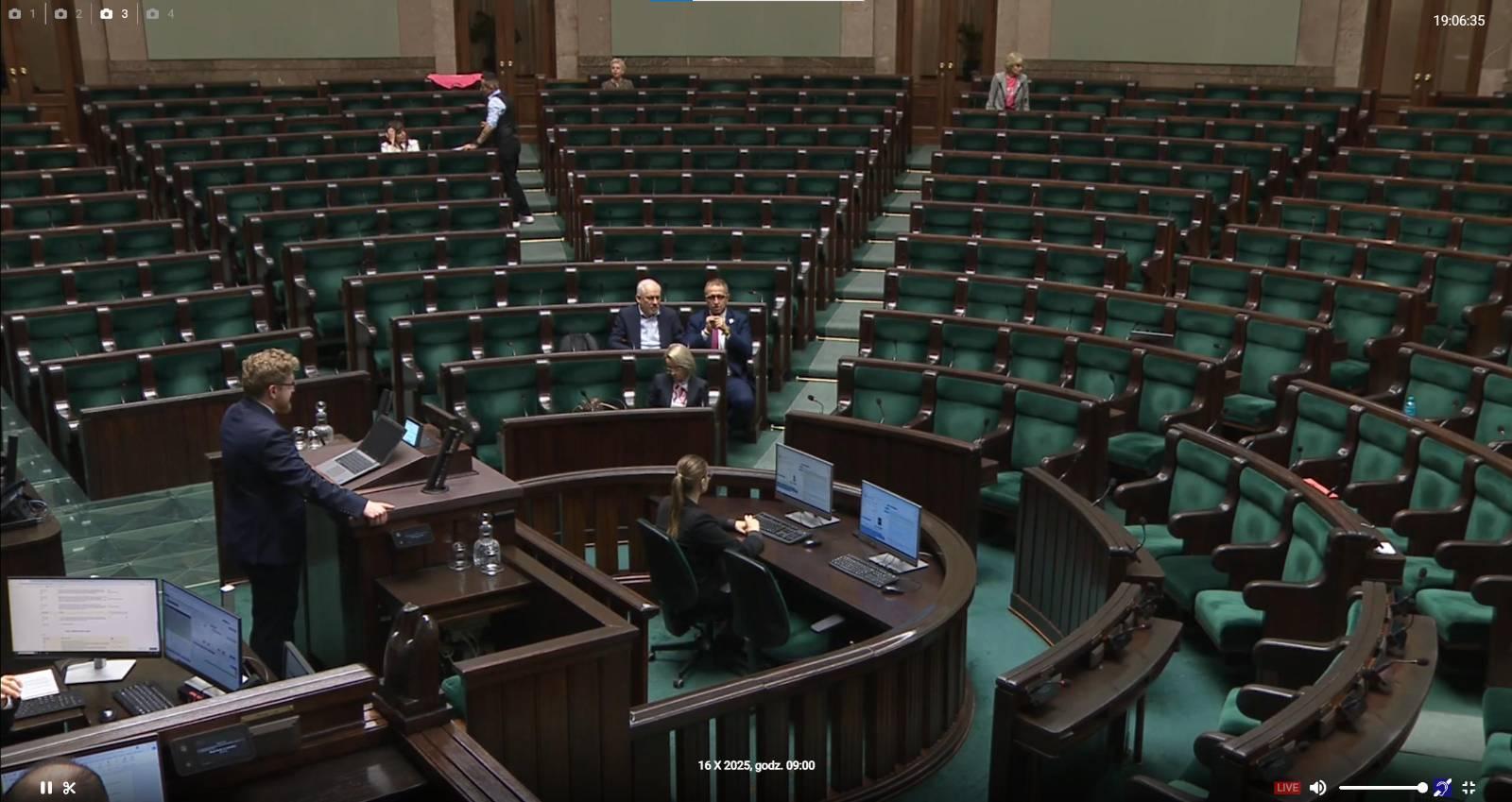 Zdjęcie sali plenarnej Sejmu RP. Przy mównicy wiceminister cyfryzacji Dariusz Standerski. Na sali - pusto (dosłownie 6 osób).